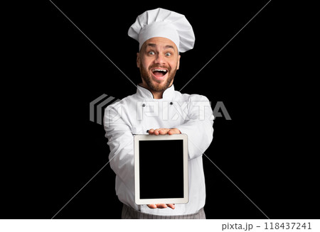 Excited Chef Showing Digital Tablet With Empty Screen Recommending Restaurant Menu Or Food Delivery Service Posing On Black Studio Background. 118437241