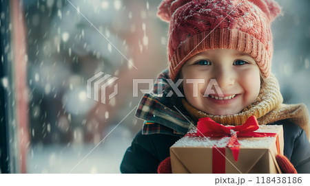 雪降る景色とプレゼントボックスを抱え笑顔を見せる女の子 118438186