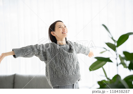 リビングで伸びをする女性 118438287