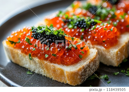 Close-up of toast slices topped with red caviar, black caviar, and fresh herbs on a plate, showcasing luxurious appetizer or hors d'oeuvre 118439505