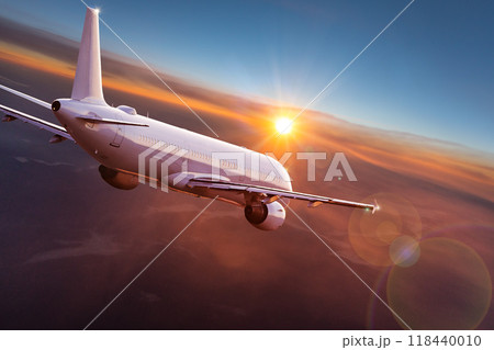Passengers commercial airplane flying above clouds in sunset light. Concept of fast travel, holidays and business. 118440010