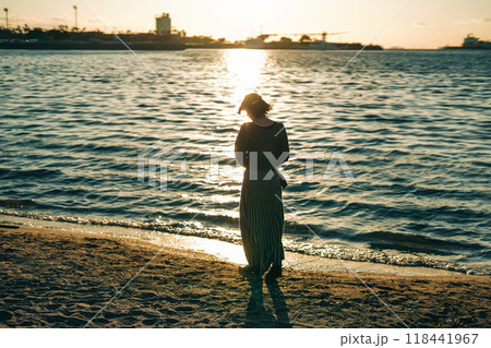 海で夕日を眺めながら歩く女性 海で夕日を眺めながら歩く女性 118441967