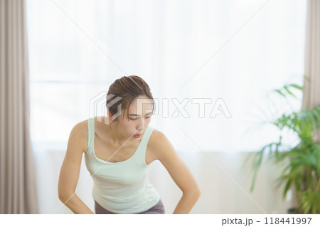 オンラインヨガサロンを自宅で受講してポーズをする若い女性 オンラインヨガサロンを自宅で受講してポーズをする若い女性 118441997