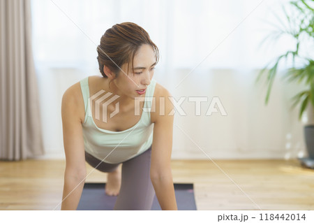 オンラインヨガサロンを自宅で受講してポーズをする若い女性 118442014