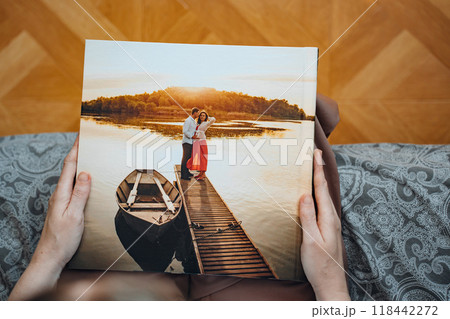 woman is holding and flipping through a photo book with a pregnancy photo shoot 118442272