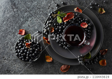 Black chokeberry drink and fresh berries on a black stone table. Black chokeberry drink and fresh berries on a black stone table. 118443619
