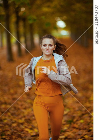 trendy 40 years old woman in fitness clothes in park running trendy 40 years old woman in fitness clothes in park running 118443707