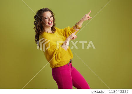 smiling modern woman pointing isolated on green smiling modern woman pointing isolated on green 118443825