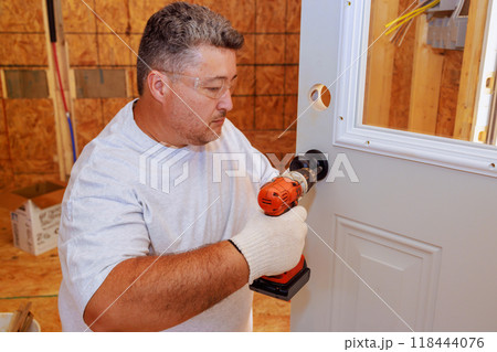Installing lock doorknob with screwdriver by professional locksmith 118444076