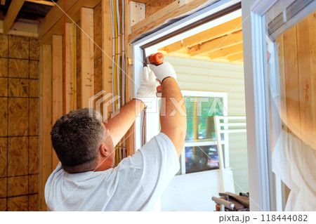Carpenter uses screwdriver to install new home front door Carpenter uses screwdriver to install new home front door 118444082