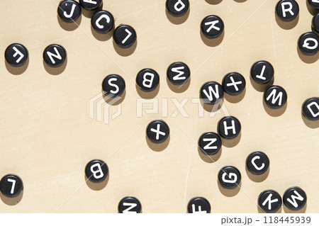 Scattered black alphabet letter beads on beige background for creative education 118445939