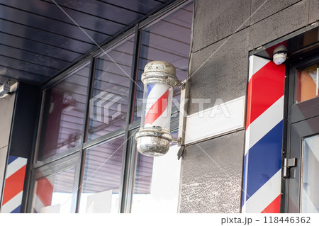 There is a red, white, and blue barber pole displayed on the side of a building 118446362