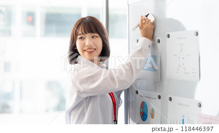 ホワイトボードを使ってプレゼンをする若いビジネスウーマン ホワイトボードを使ってプレゼンをする若いビジネスウーマン 118446397