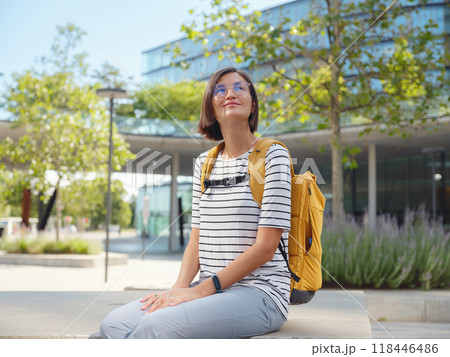 Asian woman with yellow backpack over background of modern urban architecture in Vienna. charming pensive female hipster admire cityscape of modern Vienna city 118446486