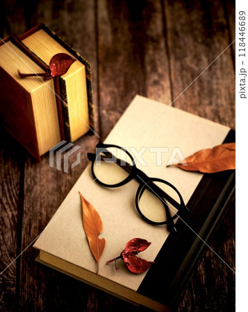 木製のテーブルに置かれた本と眼鏡と枯れ葉 118446689
