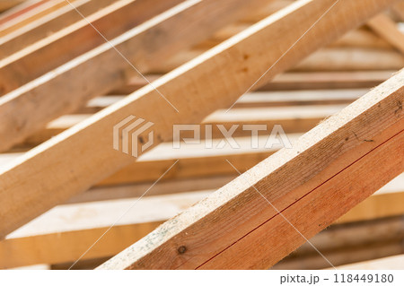 Wooden house roof is under construction. Rafters and beams are in a row Wooden house roof is under construction. Rafters and beams are in a row 118449180