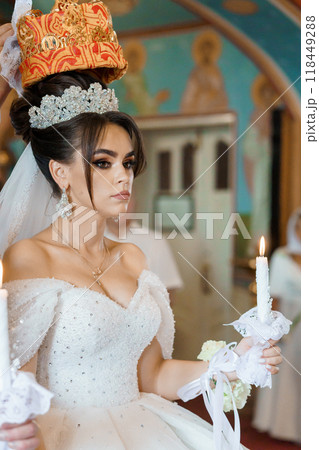 Elegant Bride in Traditional Ceremony Holding Candle with Ornate Crown and Delicate Tiara Elegant Bride in Traditional Ceremony Holding Candle with Ornate Crown and Delicate Tiara 118449288