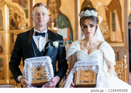 Elegant Orthodox Wedding Ceremony with Bride and Groom in Ornate Church Setting Elegant Orthodox Wedding Ceremony with Bride and Groom in Ornate Church Setting 118449300