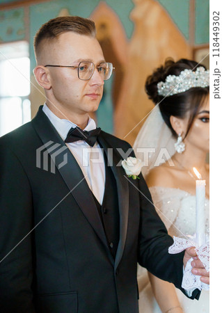 Groom Holding Candle During Elegant Church Wedding Ceremony 118449302