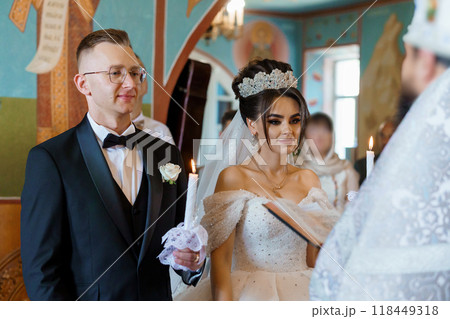 Elegant Wedding Ceremony in Ornate Church with Bride and Groom Holding Candles Elegant Wedding Ceremony in Ornate Church with Bride and Groom Holding Candles 118449318