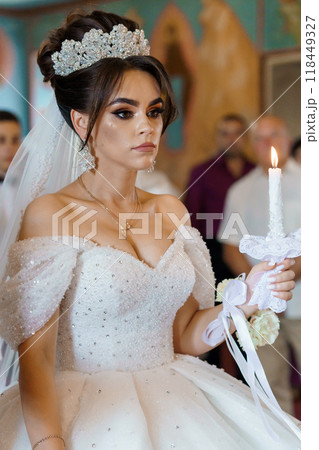 Elegant Bride Holding Candle in Sparkling Wedding Gown and Intricate Tiara During Ceremony Elegant Bride Holding Candle in Sparkling Wedding Gown and Intricate Tiara During Ceremony 118449327