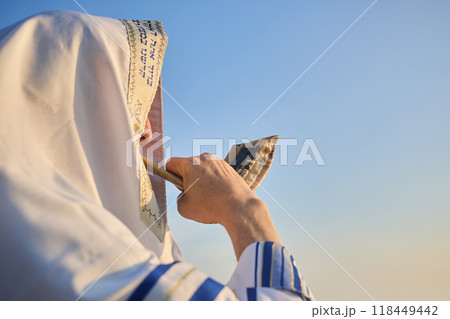 Jewish man blowing the Shofar rams horn on Rosh Hashanah and Yom Kippur day. 118449442