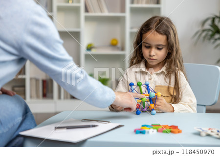Cute long-haired girl looking busy while having a tutorial with a speech therapist Cute long-haired girl looking busy while having a tutorial with a speech therapist 118450970