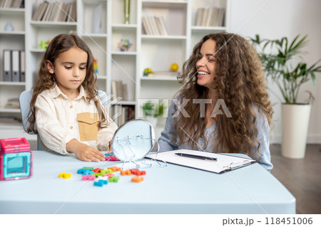 Good-looking young speech therapist working with a cute girl on her articulation 118451006
