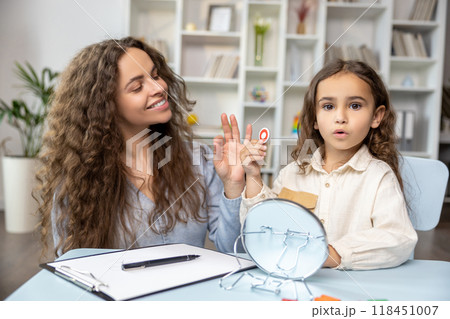 Child and doctor working on articulation and looking contented and concentrated Child and doctor working on articulation and looking contented and concentrated 118451007