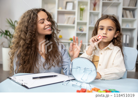 Child and doctor working on articulation and looking contented and concentrated Child and doctor working on articulation and looking contented and concentrated 118451019