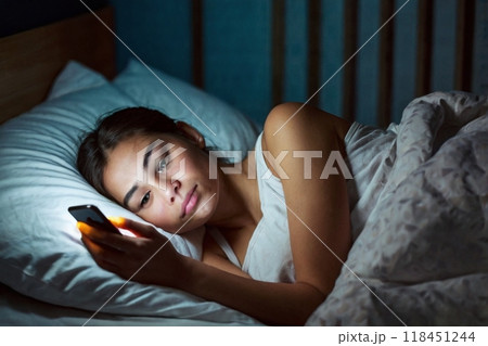 夜ベッドの中でスマホを見ている女性 118451244