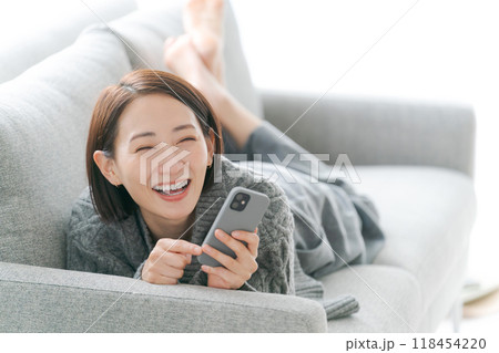 ソファーでスマホを使う女性 118454220