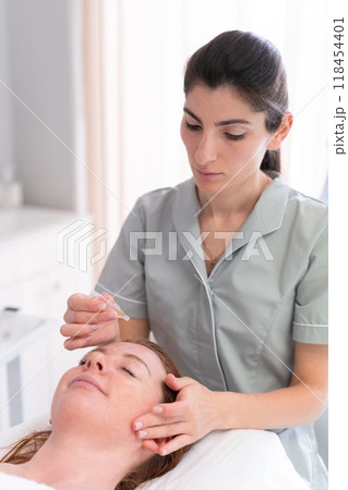 Woman receiving serum oil treatment in beauty Woman receiving serum oil treatment in beauty 118454401