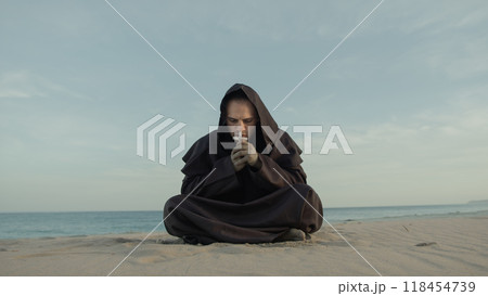 Monk Collected In Prayer Sitting On The Beach In The Evening 118454739