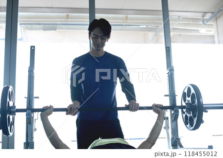 ジムでパーソナルトレーニングでベンチプレスをする男性を補助する男性インストラクター ジムでパーソナルトレーニングでベンチプレスをする男性を補助する男性インストラクター 118455012