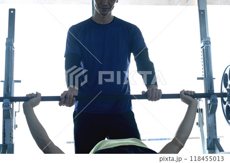ジムでパーソナルトレーニングでベンチプレスをする男性を補助する男性インストラクター ジムでパーソナルトレーニングでベンチプレスをする男性を補助する男性インストラクター 118455013