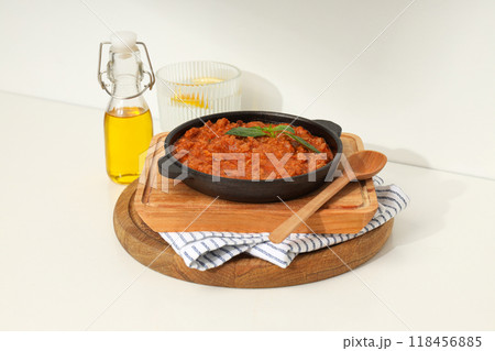 Bolognese sauce in frying pan, wooden boards, glass of water and bottle of oil on light background Bolognese sauce in frying pan, wooden boards, glass of water and bottle of oil on light background 118456885