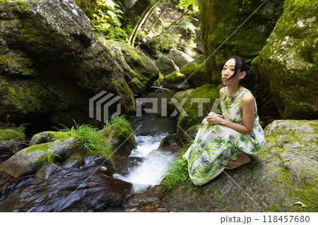 渓流の苔むした岩に座る女性 118457680
