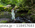 渓流の苔むした岩に座り水に足をつける女性 118457683