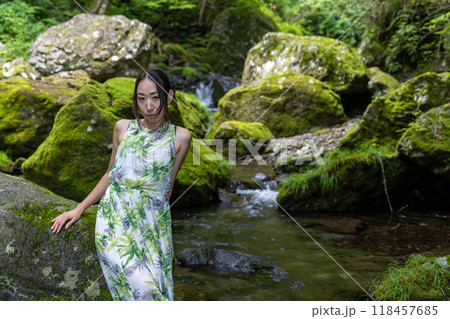 渓流の苔むした岩に座る女性 118457685