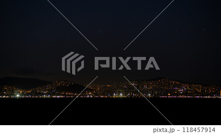 The city of Istanbul glows under the night sky, showcasing vibrant lights along the coast, creating a serene and captivating waterfront atmosphere. 118457914