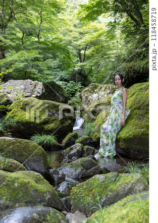 渓流の苔むした岩に座る女性 118458719