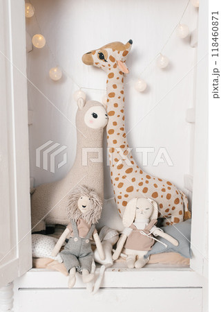 Giraffe and llama are sitting on a bed with a rabbit in children room Giraffe and llama are sitting on a bed with a rabbit in children room 118460871
