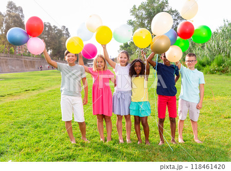 Cheerful tweenagers with colored balloons posing together in summer park 118461420