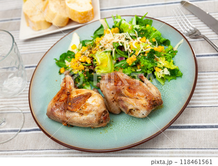 Fried quail garnished with portion of fresh vegetable salad 118461561