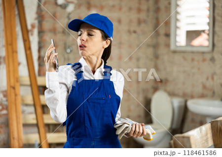 Woman builder using smartphone while standing in renovated room Woman builder using smartphone while standing in renovated room 118461586