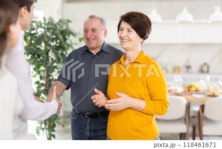 Elderly parents with open arms greeting son with wife at home 118461671
