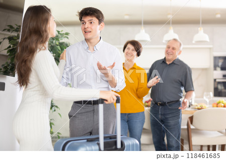Happy young girl coming to meet boyfriend's family. Elderly mother, father and young guy joyfully greeting at door Happy young girl coming to meet boyfriend's family. Elderly mother, father and young guy joyfully greeting at door 118461685