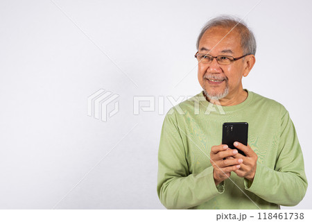 Portrait smiling Asian older man smiling holding a cell phone studio shot isolated on white background. elderly typing message on mobile phone in hand. Concept of connection and communication Portrait smiling Asian older man smiling holding a cell phone studio shot isolated on white background. elderly typing message on mobile phone in hand. Concept of connection and communication 118461738