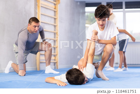 Diligent preteen student twisting his opponent's arm on the floor 118461751
